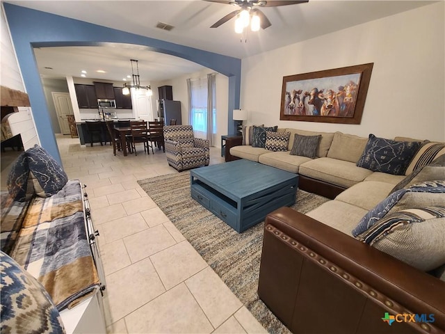 living room featuring ceiling fan with notable chandelier and light tile patterned floors