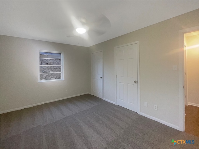 unfurnished bedroom featuring ceiling fan and dark colored carpet