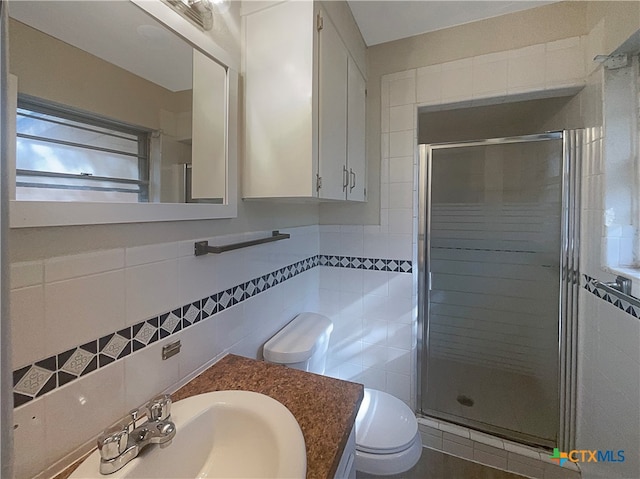 bathroom featuring tile walls, toilet, and a shower with door