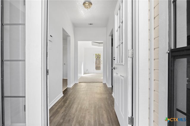 hall featuring a textured ceiling and dark wood-type flooring