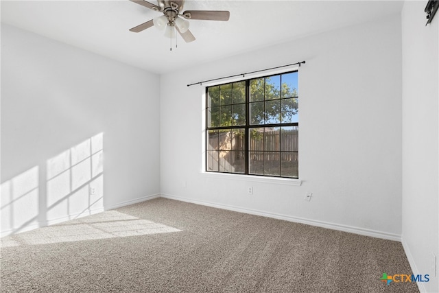 carpeted empty room featuring a barn door and ceiling fan