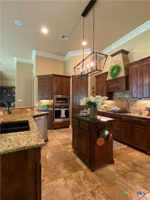 kitchen with a sink, stainless steel appliances, tasteful backsplash, a center island, and ornamental molding
