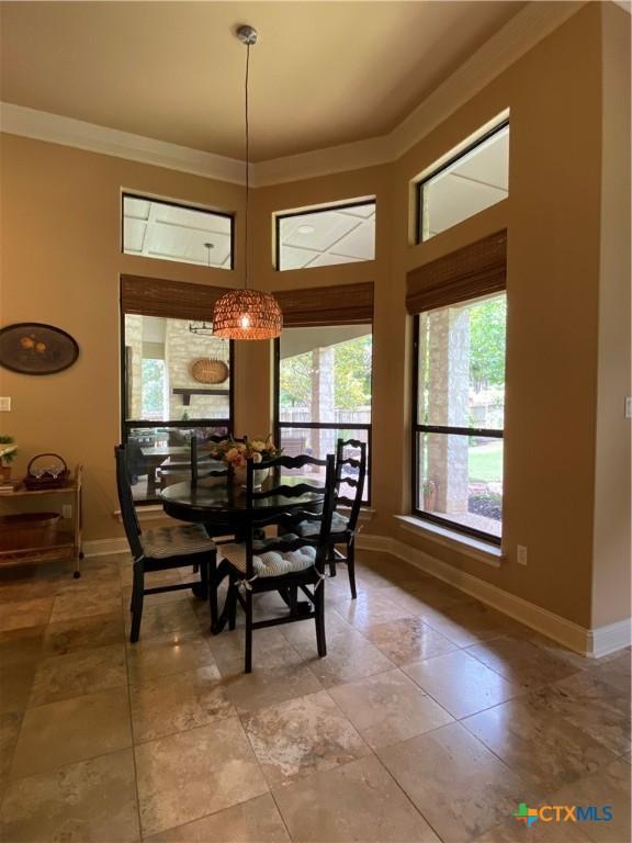 dining room with crown molding, a towering ceiling, and baseboards
