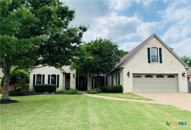 view of front of house with concrete driveway, a front yard, an attached garage, and stone siding