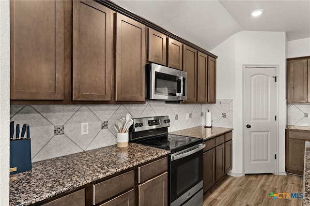6505 Cassidy Ln, Killeen, TX 76542 - kitchen featuring appliances with stainless steel finishes, light wood finished floors, dark stone countertops, vaulted ceiling, and dark brown cabinetry