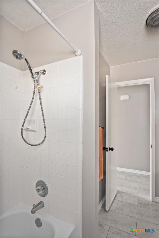 bathroom with tiled shower / bath combo and a textured ceiling