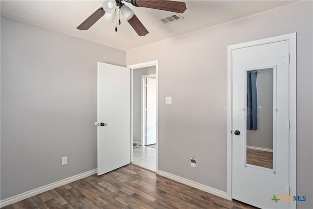 unfurnished bedroom featuring ceiling fan and dark wood-type flooring