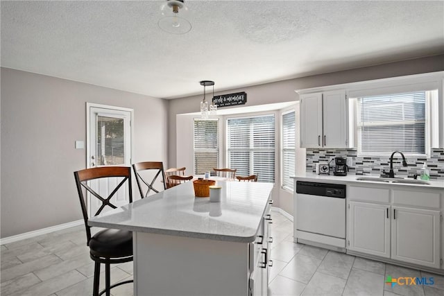 kitchen with white dishwasher, sink, white cabinets, a center island, and hanging light fixtures