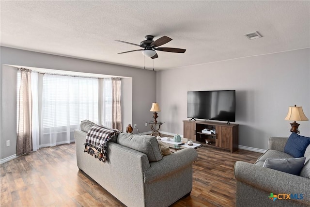 living room with a textured ceiling, dark hardwood / wood-style floors, and ceiling fan