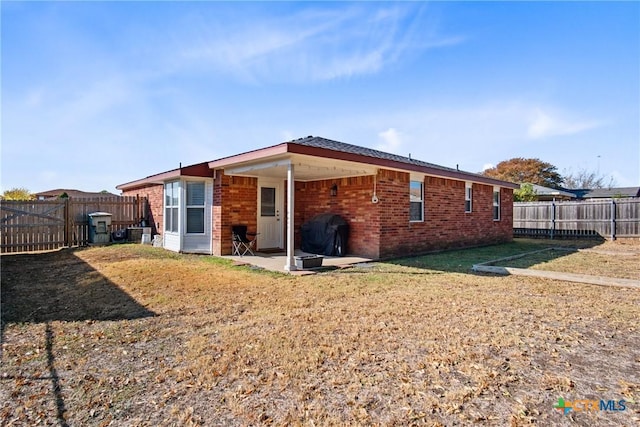 rear view of property featuring a lawn and a patio