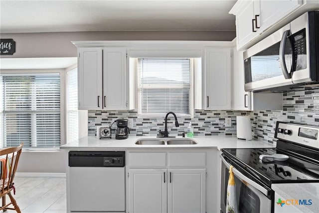 kitchen with a wealth of natural light, sink, white cabinets, and appliances with stainless steel finishes