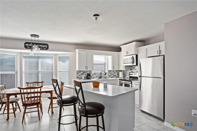 kitchen with a center island, white cabinetry, a healthy amount of sunlight, and appliances with stainless steel finishes