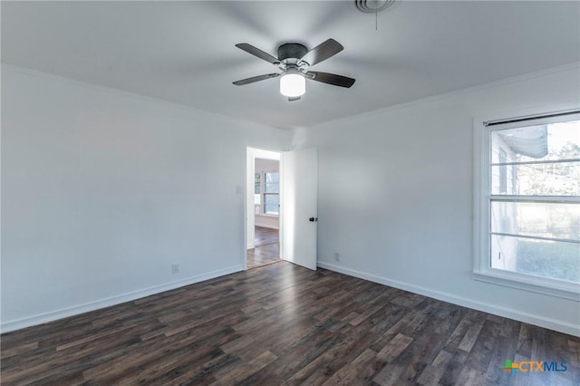 empty room with dark hardwood / wood-style floors, a wealth of natural light, ornamental molding, and ceiling fan