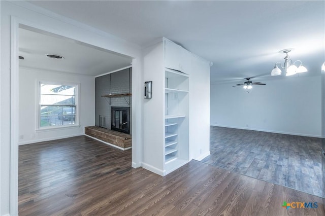 unfurnished living room featuring ceiling fan with notable chandelier, dark hardwood / wood-style flooring, ornamental molding, and a fireplace