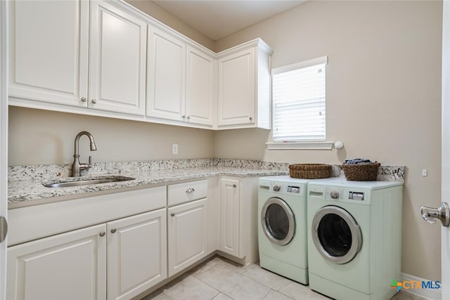 clothes washing area featuring light tile patterned floors, washer and clothes dryer, a sink, and cabinet space