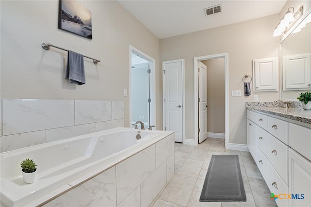 full bath with a bath, vanity, visible vents, and baseboards