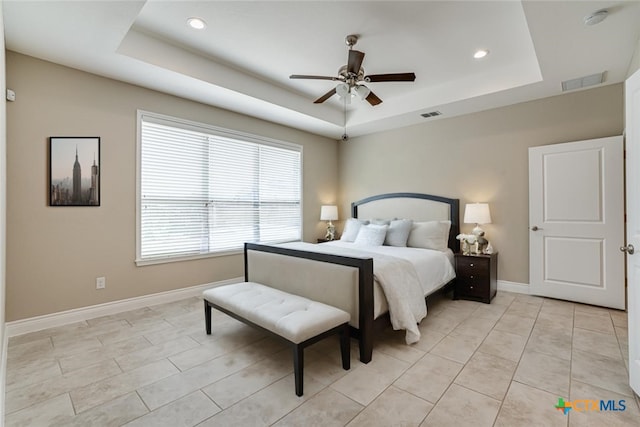 bedroom with baseboards, visible vents, and a raised ceiling