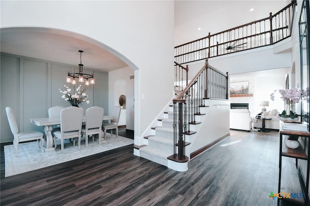 194 Panorama Ln, Victoria, TX 77905 - stairs featuring a high ceiling, wood finished floors, a fireplace, a chandelier, and arched walkways