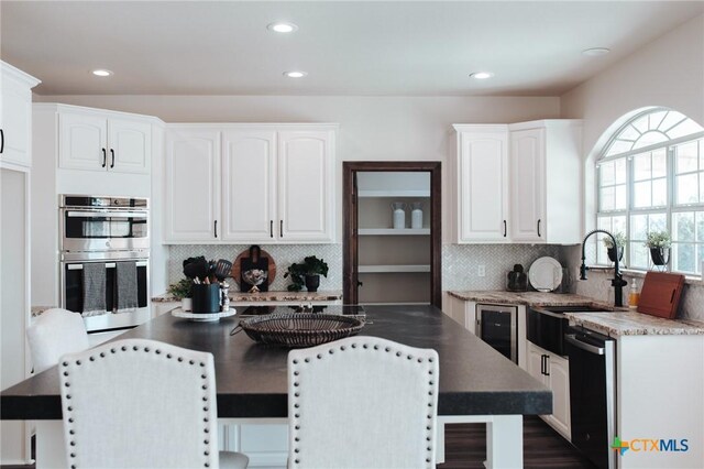 194 Panorama Ln, Victoria, TX 77905 - kitchen featuring a sink, stainless steel double oven, white cabinetry, dishwasher, and backsplash