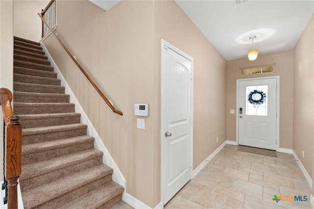 foyer entrance with stairs and baseboards