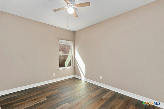 spare room with ceiling fan, dark wood-type flooring, and baseboards