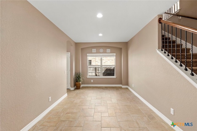 interior space with baseboards, recessed lighting, stairs, stone finish flooring, and a textured wall