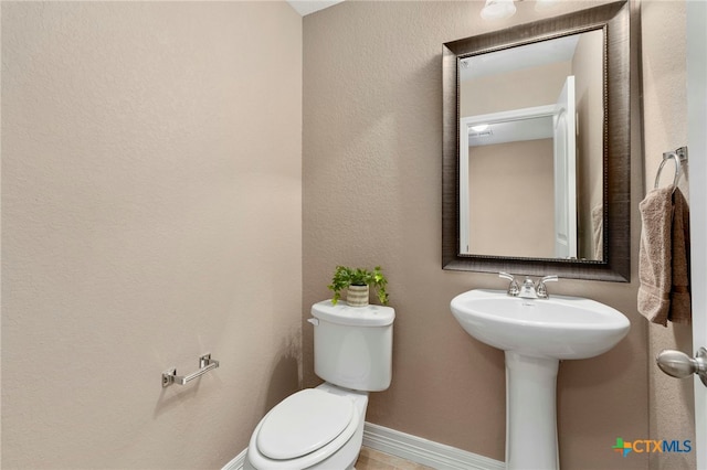 bathroom featuring baseboards and toilet