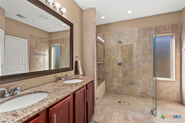 full bath with double vanity, visible vents, a stall shower, and a sink