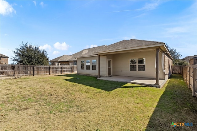 rear view of property featuring a yard, a fenced backyard, and a patio area