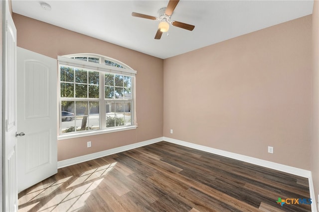 unfurnished room featuring a ceiling fan, dark wood-type flooring, and baseboards