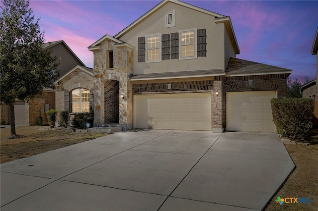 traditional-style home with stucco siding, brick siding, a garage, and concrete driveway