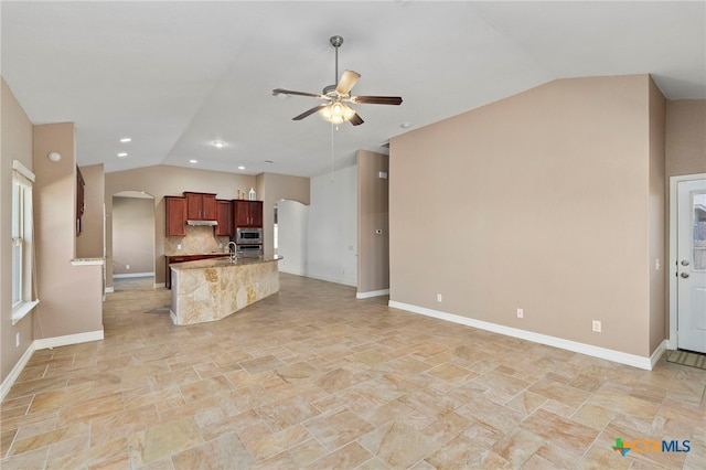 kitchen with a sink, arched walkways, lofted ceiling, and open floor plan