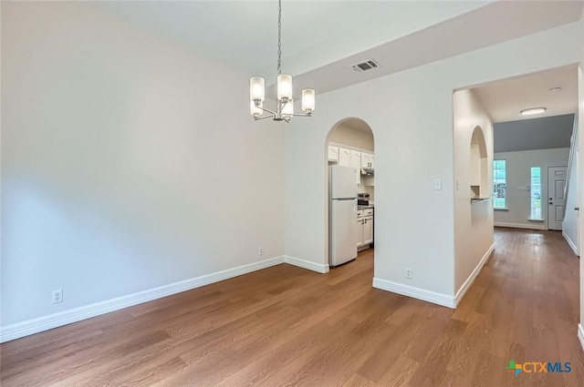 2033 Northview Dr, San Marcos, TX 78666 - spare room featuring arched walkways, wood finished floors, and a chandelier