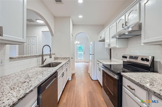 2033 Northview Dr, San Marcos, TX 78666 - kitchen featuring appliances with stainless steel finishes, under cabinet range hood, arched walkways, light wood-style floors, and tasteful backsplash