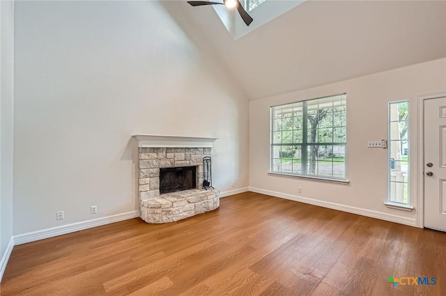2033 Northview Dr, San Marcos, TX 78666 - unfurnished living room featuring ceiling fan, high vaulted ceiling, wood finished floors, a fireplace, and a skylight