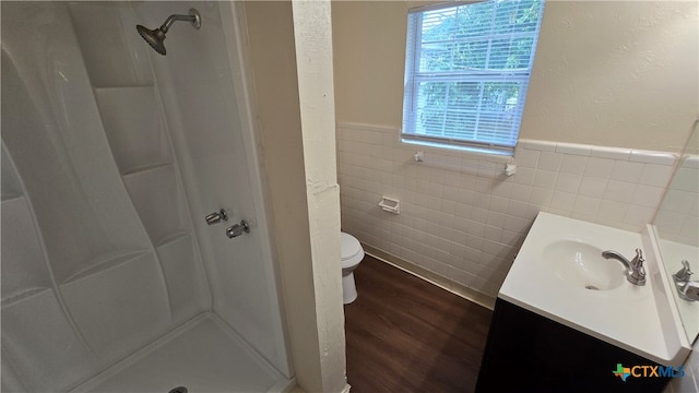 bathroom with hardwood / wood-style flooring, vanity, a shower, toilet, and tile walls