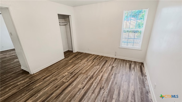 unfurnished bedroom with a closet and dark hardwood / wood-style flooring