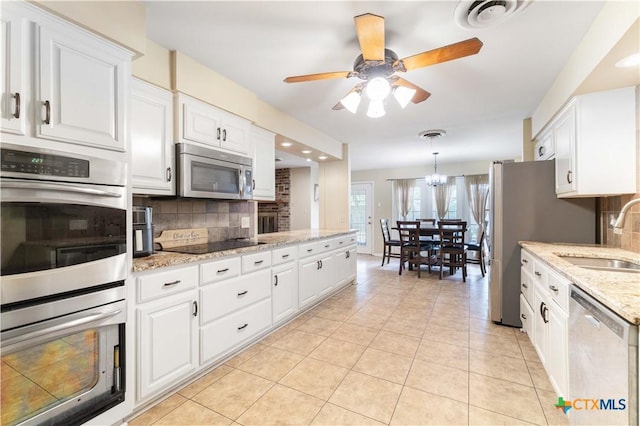 204 W Johnson St, Cuero, TX 77954 - kitchen with appliances with stainless steel finishes, decorative backsplash, white cabinetry, a ceiling fan, and light tile patterned floors