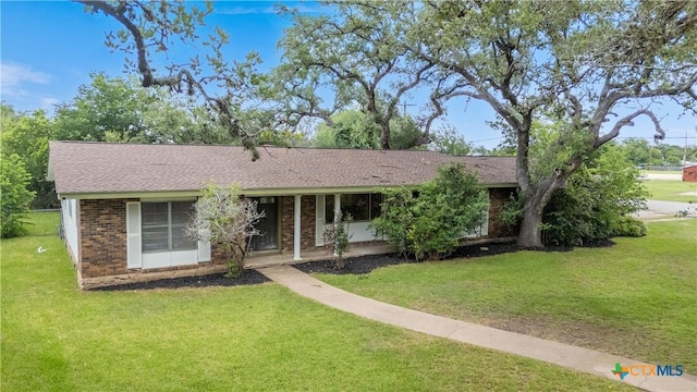 204 W Johnson St, Cuero, TX 77954 - ranch-style house with brick siding, a front yard, and a shingled roof