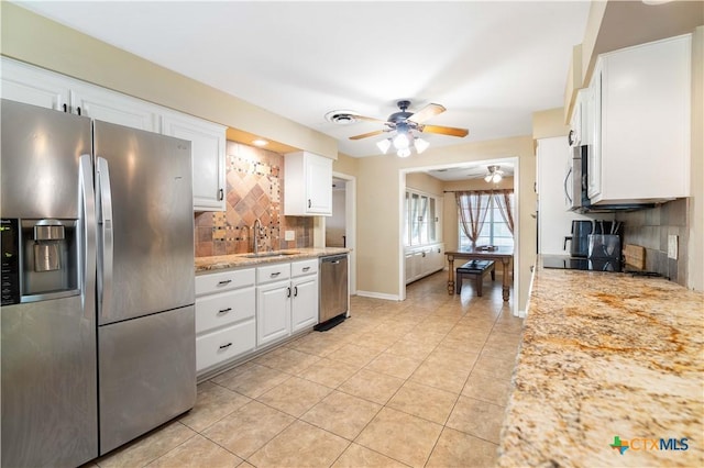 204 W Johnson St, Cuero, TX 77954 - kitchen featuring stainless steel appliances, a ceiling fan, tasteful backsplash, white cabinetry, and light tile patterned floors