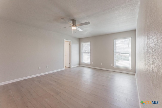 spare room featuring a ceiling fan, a textured ceiling, baseboards, and wood finished floors