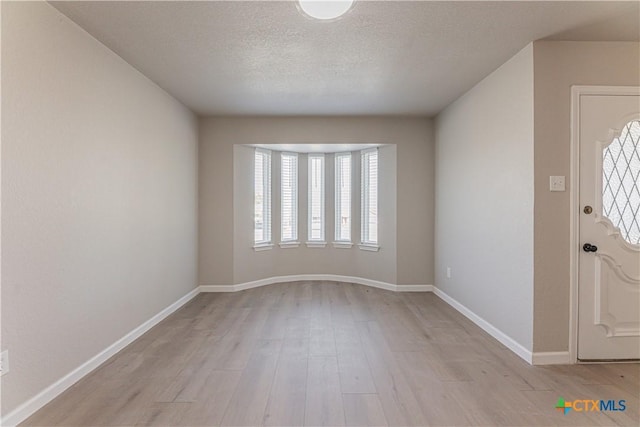 interior space with light wood-style floors, baseboards, and a textured ceiling