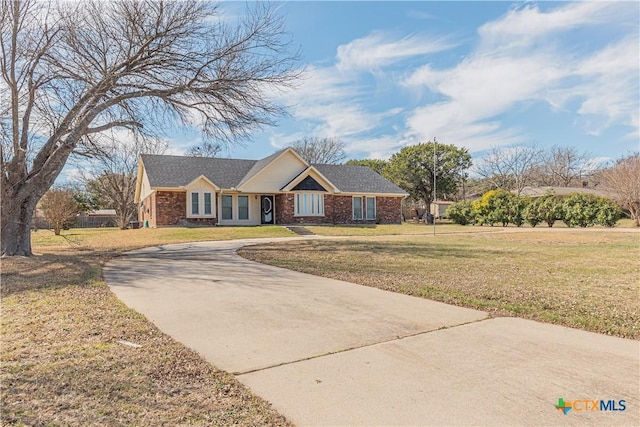 view of front of property with concrete driveway, brick siding, and a front yard