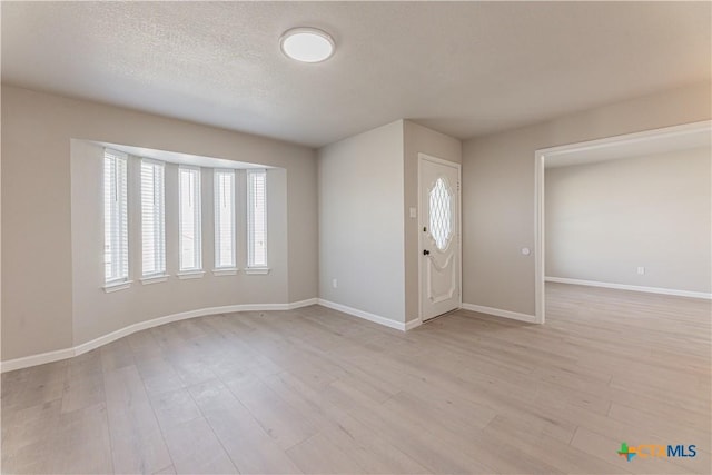 entrance foyer with light wood-style floors, baseboards, and a textured ceiling