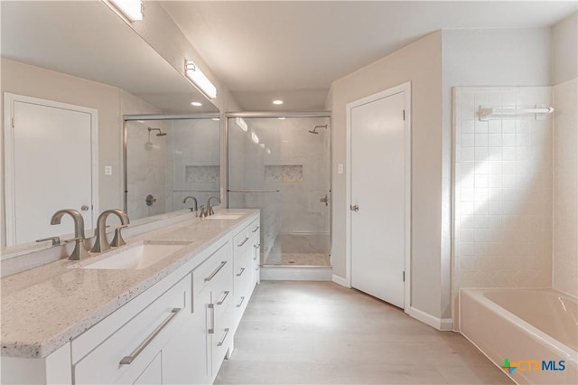 bathroom with a stall shower, a sink, and wood finished floors