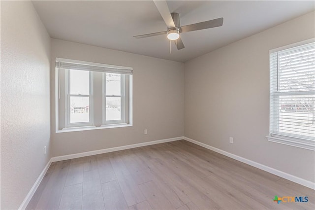 unfurnished room featuring ceiling fan, light wood-style flooring, and baseboards