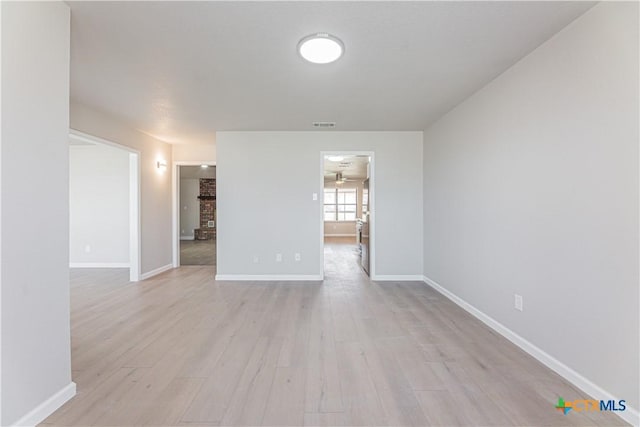 unfurnished room featuring light wood-style floors, visible vents, and baseboards