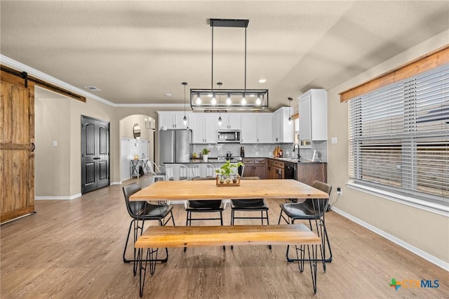 1442 Neff Dr, Copperas Cove, TX 76522 - dining area with light wood-style floors, arched walkways, crown molding, and a barn door