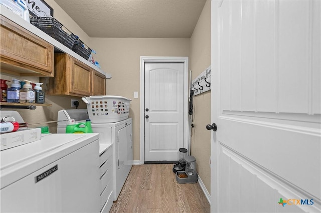 1442 Neff Dr, Copperas Cove, TX 76522 - washroom featuring washing machine and clothes dryer, light wood-style flooring, cabinet space, and a textured ceiling