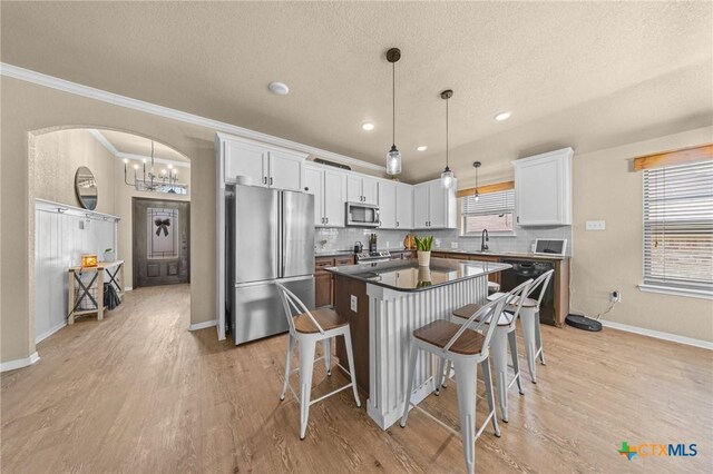 1442 Neff Dr, Copperas Cove, TX 76522 - kitchen featuring appliances with stainless steel finishes, arched walkways, a textured ceiling, white cabinetry, and a breakfast bar